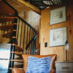 Wood-paneled interior with spiral staircase, leather chair, and cozy decor in a Fairbanks Alaska treehouse rental
