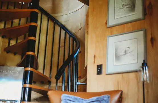 Wood-paneled interior with spiral staircase, leather chair, and cozy decor in a Fairbanks Alaska treehouse rental