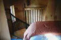 Cozy loft bedroom with wood walls and spiral staircase in a Fairbanks Alaska adventure lodge or treehouse rental