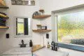 Modern double-sink bathroom with black fixtures and wood shelving in a Fairbanks Alaska treehouse rental.