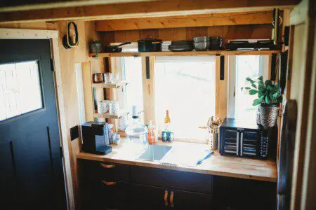 Wood and black kitchen with large windows, coffee setup, and natural light in a Fairbanks Alaska treehouse rental
