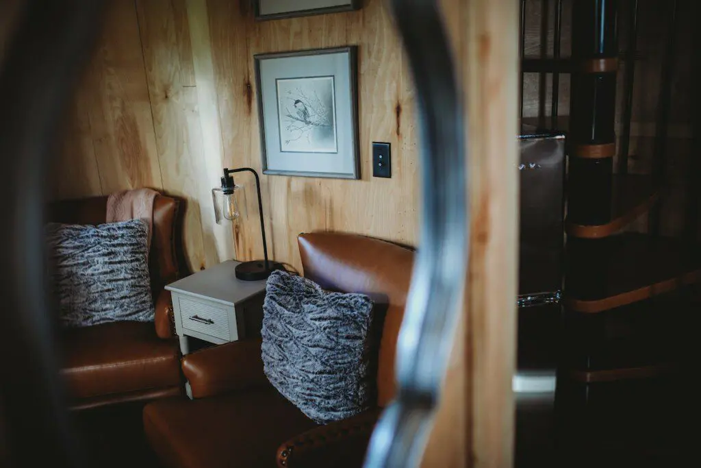 Warm and cozy seating nook with leather chairs and wood walls in an Alaska adventure lodge or Fairbanks treehouse