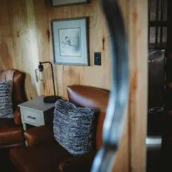 Warm and cozy seating nook with leather chairs and wood walls in an Alaska adventure lodge or Fairbanks treehouse
