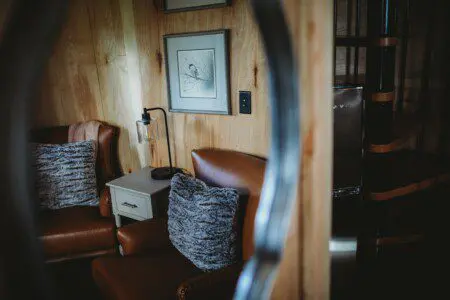 Warm and cozy seating nook with leather chairs and wood walls in an Alaska adventure lodge or Fairbanks treehouse