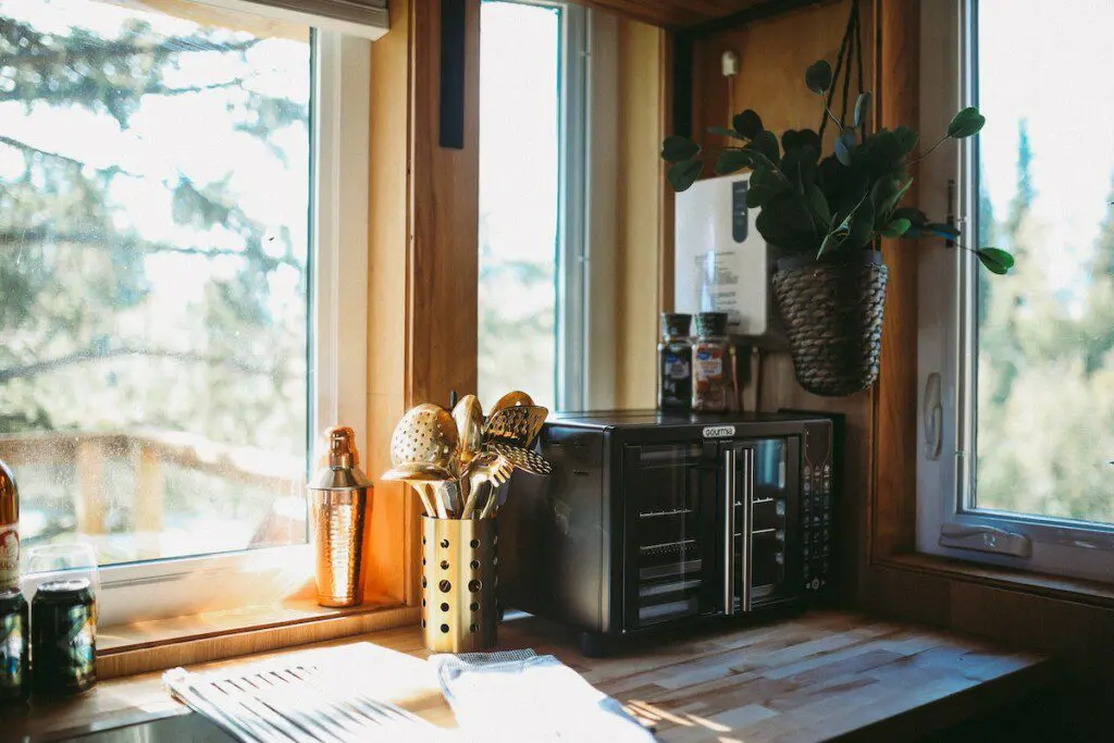 Rustic kitchenette with wooden shelves, water dispenser, mugs, and coffee essentials in a Fairbanks Alaska treehouse
