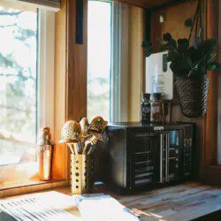 Rustic kitchenette with wooden shelves, water dispenser, mugs, and coffee essentials in a Fairbanks Alaska treehouse