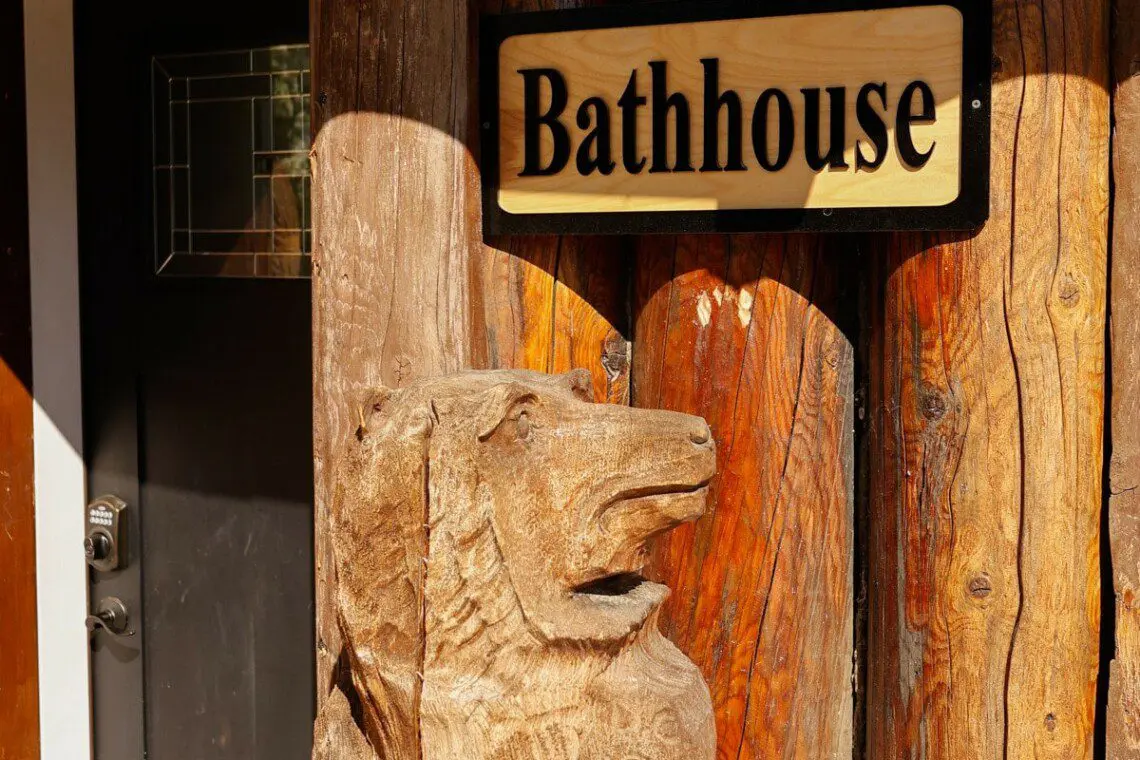 Wooden bathhouse sign mounted on a log wall at a rustic lodge in Fairbanks, Alaska