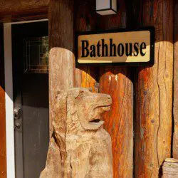 Wooden bathhouse sign mounted on a log wall at a rustic lodge in Fairbanks, Alaska