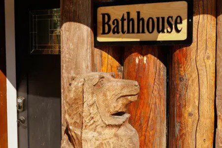 Wooden bathhouse sign mounted on a log wall at a rustic lodge in Fairbanks, Alaska
