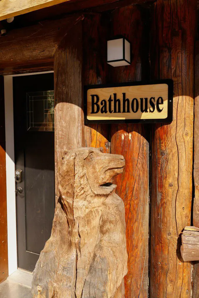 Wooden bathhouse sign mounted on a log wall at a rustic lodge in Fairbanks, Alaska