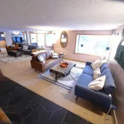 Spacious and modern living room in a Fairbanks lodge featuring cozy seating, rustic decor, and large windows with natural light.