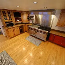 Spacious dining room with a large wooden table, modern chairs, and floor-to-ceiling windows showcasing a snowy forest at an Alaska lodge.