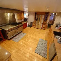 Spacious dining room with a large wooden table, modern chairs, and floor-to-ceiling windows showcasing a snowy forest at an Alaska lodge.