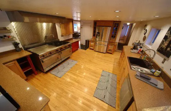 Spacious dining room with a large wooden table, modern chairs, and floor-to-ceiling windows showcasing a snowy forest at an Alaska lodge.