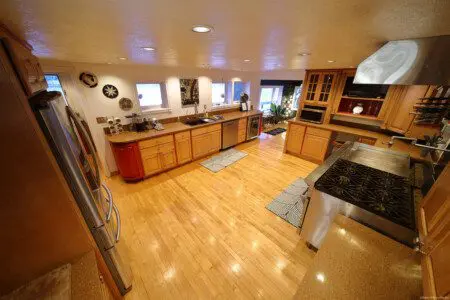 Spacious dining room with a large wooden table, modern chairs, and floor-to-ceiling windows showcasing a snowy forest at an Alaska lodge.