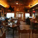 Rustic wood interior of an Alaskan lodge-style restaurant with guests dining under warm lighting