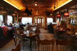 Rustic wood interior of an Alaskan lodge-style restaurant with guests dining under warm lighting