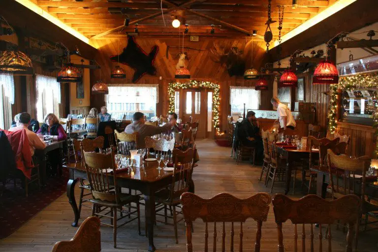 Rustic wood interior of an Alaskan lodge-style restaurant with guests dining under warm lighting