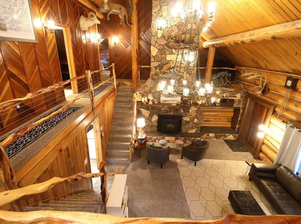 Cozy log cabin living room with stone fireplace, modern sofa, and wood carvings in Fairbanks Alaska