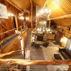 Cozy log cabin living room with stone fireplace, modern sofa, and wood carvings in Fairbanks Alaska