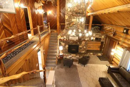 Cozy log cabin living room with stone fireplace, modern sofa, and wood carvings in Fairbanks Alaska