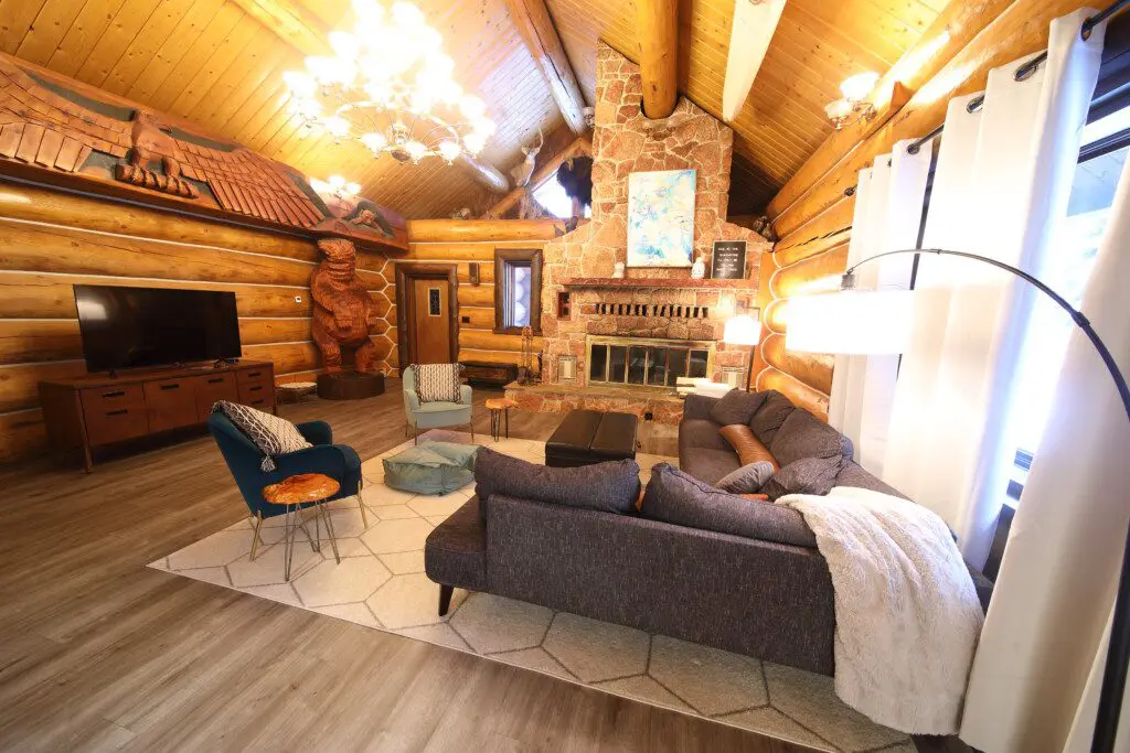 Cozy log cabin living room with stone fireplace, modern sofa, and wood carvings in Fairbanks Alaska