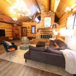 Cozy log cabin living room with stone fireplace, modern sofa, and wood carvings in Fairbanks Alaska