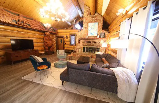 Cozy log cabin living room with stone fireplace, modern sofa, and wood carvings in Fairbanks Alaska
