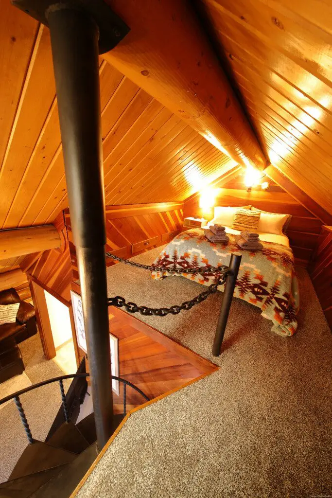 Rustic cabin bedroom with tribal blanket, soft lighting, and wooden walls in a Fairbanks, Alaska treehouse rental.