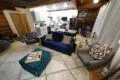 Modern open-concept living area with navy couch, kitchen, and spiral staircase in a Fairbanks Alaska treehouse rental