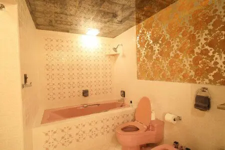 Retro-style bathroom with dual pink sinks, large mirrors, and warm vanity lighting in a Fairbanks Alaska lodge