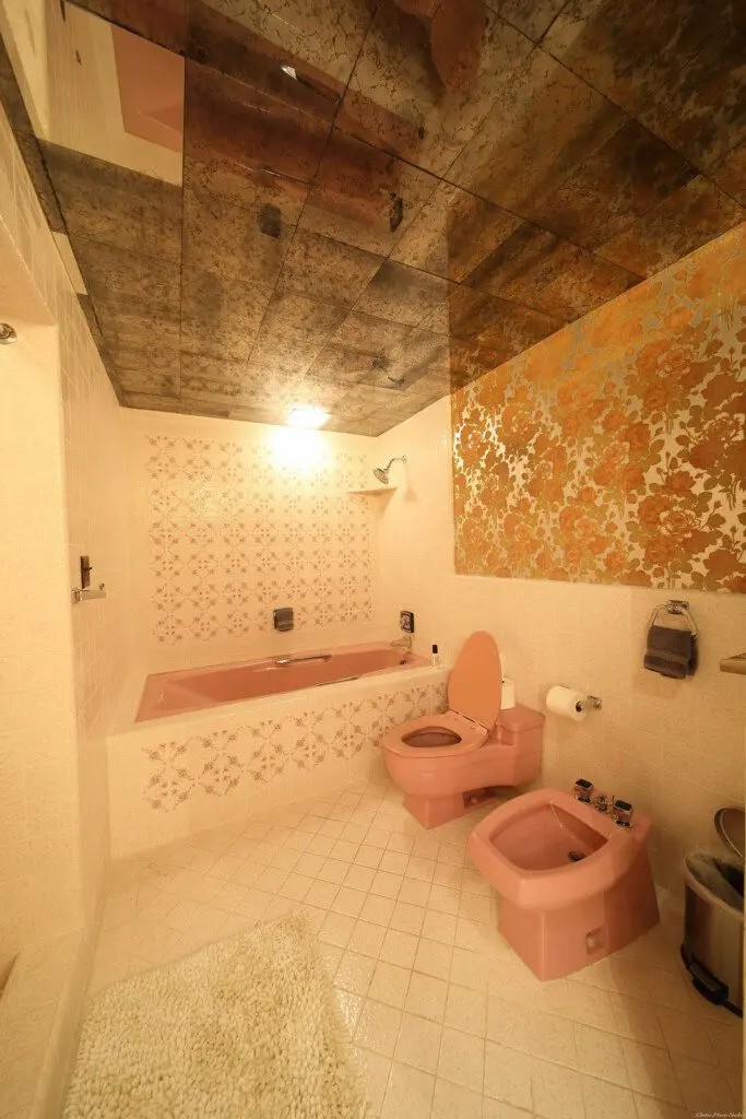 Retro-style bathroom with dual pink sinks, large mirrors, and warm vanity lighting in a Fairbanks Alaska lodge