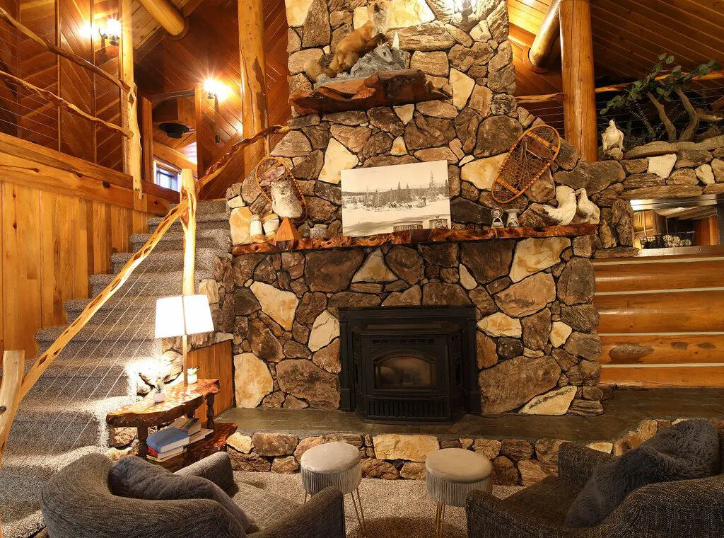 Cozy log cabin living room with stone fireplace, modern sofa, and wood carvings in Fairbanks Alaska