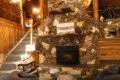 Cozy log cabin living room with stone fireplace, modern sofa, and wood carvings in Fairbanks Alaska