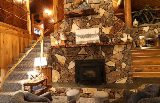 Cozy log cabin living room with stone fireplace, modern sofa, and wood carvings in Fairbanks Alaska