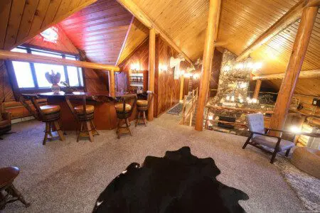 Rustic loft lounge with log walls, cozy seating, and soft carpet in a Fairbanks Alaska treehouse rental