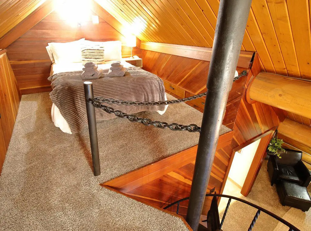 Rustic log cabin bedroom with cozy bedding and spiral staircase in Fairbanks Alaska