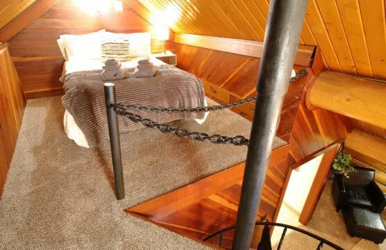Rustic log cabin bedroom with cozy bedding and spiral staircase in Fairbanks Alaska