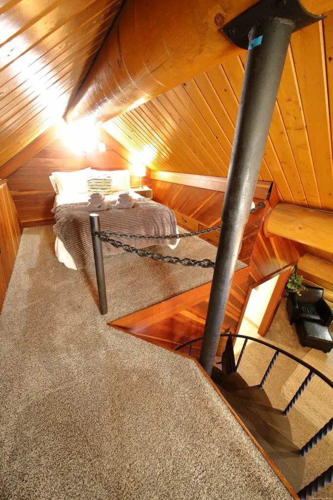 Rustic log cabin bedroom with cozy bedding and spiral staircase in Fairbanks Alaska