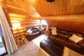 Cozy upstairs lounge with leather sofas, wood-paneled ceiling, and soft lighting at Alaska Adventure Lodge in Fairbanks, Alaska