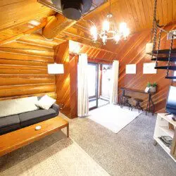 Warm log cabin living room in Fairbanks Alaska with wooden interior, couch, and spiral staircase