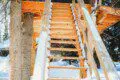 Wooden staircase built among snow-covered trees leading up to a treehouse in Fairbanks, Alaska.