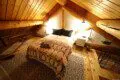 Warmly lit loft bedroom with log beams, patterned bedding, and cozy decor in a Fairbanks Alaska treehouse rental