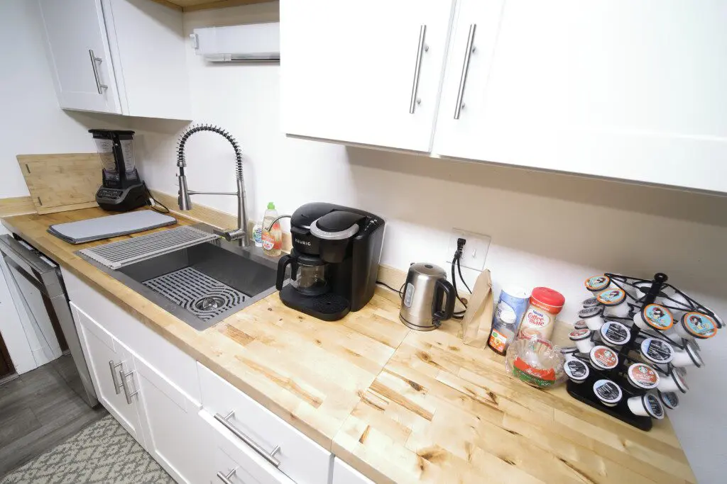 Bright rustic kitchen with white cabinets, wood countertops, and central island in a Fairbanks adventure lodge