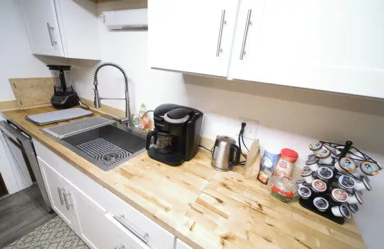 Bright rustic kitchen with white cabinets, wood countertops, and central island in a Fairbanks adventure lodge