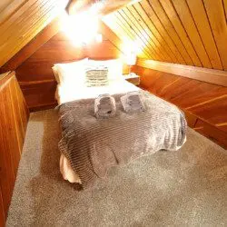 Warm wooden attic-style loft bedroom with double bed and soft lighting in Fairbanks Alaska