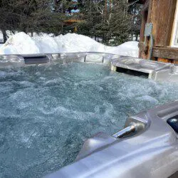 Outdoor hot tub with bubbling water next to a rustic cabin in snowy Fairbanks, Alaska.