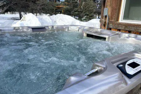 Outdoor hot tub with bubbling water next to a rustic cabin in snowy Fairbanks, Alaska.