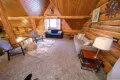 Rustic loft lounge with log walls, cozy seating, and soft carpet in a Fairbanks Alaska treehouse rental