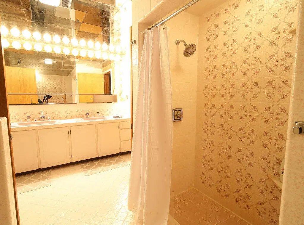 Retro-style bathroom with dual pink sinks, large mirrors, and warm vanity lighting in a Fairbanks Alaska lodge